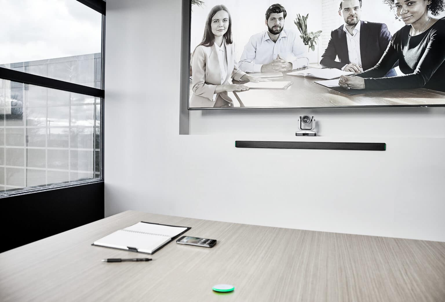 meeting space with MXA710 linear array microphone mounted on wall beneath display and MXA-NMB on the work table